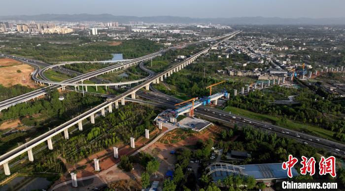 航拍正在建設(shè)的跨越成都繞城高速公路連續(xù)梁施工現(xiàn)場，旁邊依次為已運(yùn)營的成渝高速鐵路和機(jī)場高速公路?！⒅铱?攝