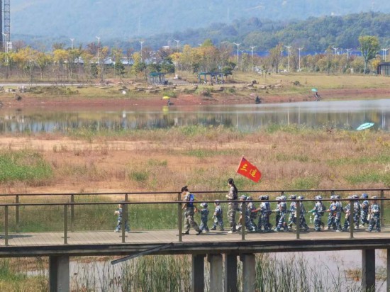 　　10月24日，秋游的幼兒園小朋友在老師帶領下走在清水塘公園里的木橋上。本報記者 常雯宜攝