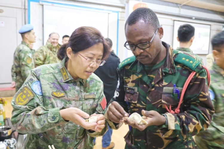 圖為維和官兵與外軍人員共同包餃子。胡光明攝