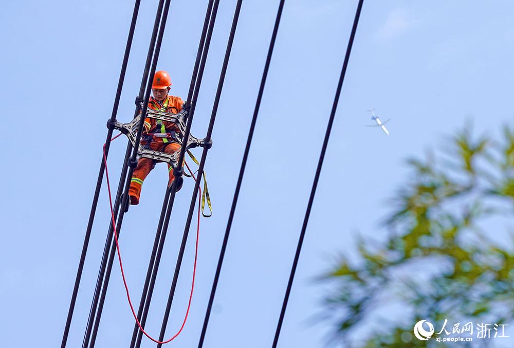 3月11日，在浙江省諸暨市河上鎮(zhèn)，浙江省送變電工程有限公司檢修人員在高空的導(dǎo)線上進(jìn)行線路檢修維護(hù)。人民網(wǎng) 章勇濤攝