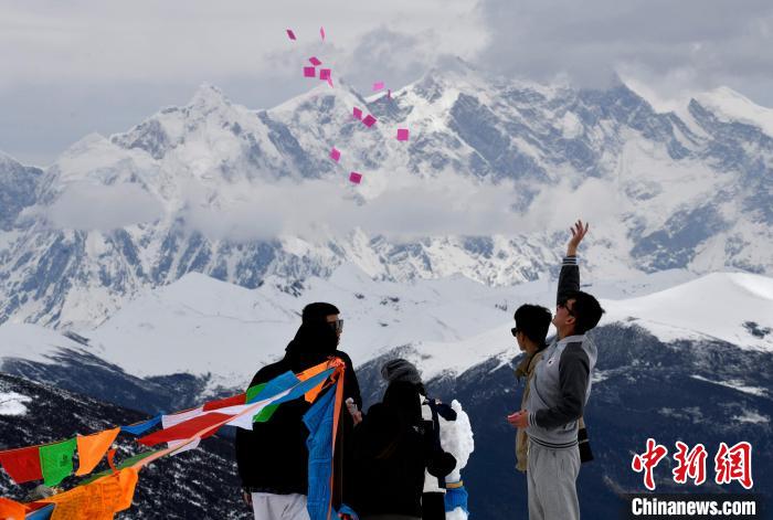 圖為5月14日，游客在西藏林芝色季拉山觀景臺(tái)拋灑“隆達(dá)”(風(fēng)馬旗，藏族民眾的一種祈福方式)?！±盍?攝