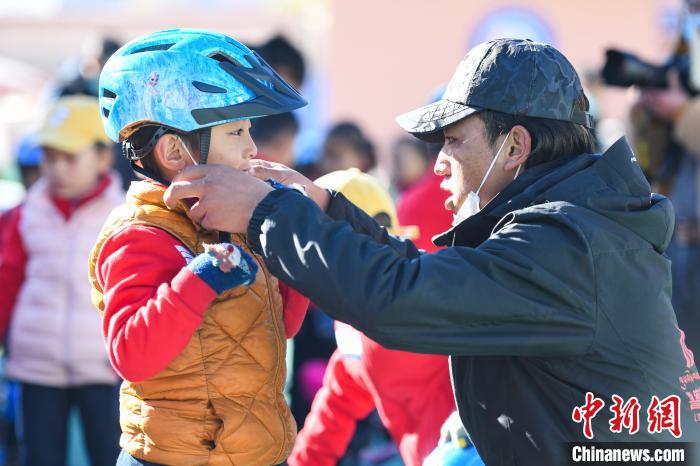 圖為拉薩市實(shí)驗(yàn)幼兒園孩子在教練的幫助下穿戴頭盔?！『闻罾?攝