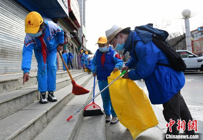 圖為拉薩市小學(xué)生打掃街道?！∝暩聛?lái)松 攝