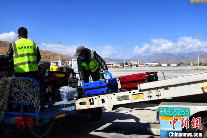 圖為機(jī)場工作人員傳送旅客行李箱?！≈芎?攝